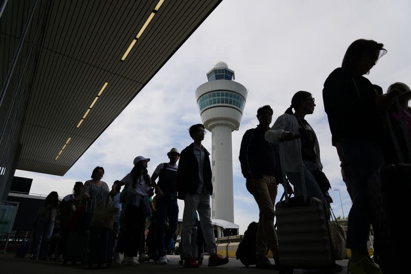 Travellers wait outside the terminal building to check in and board flights at Amsterdam's Schiphol Airport, Netherlands in this file photo