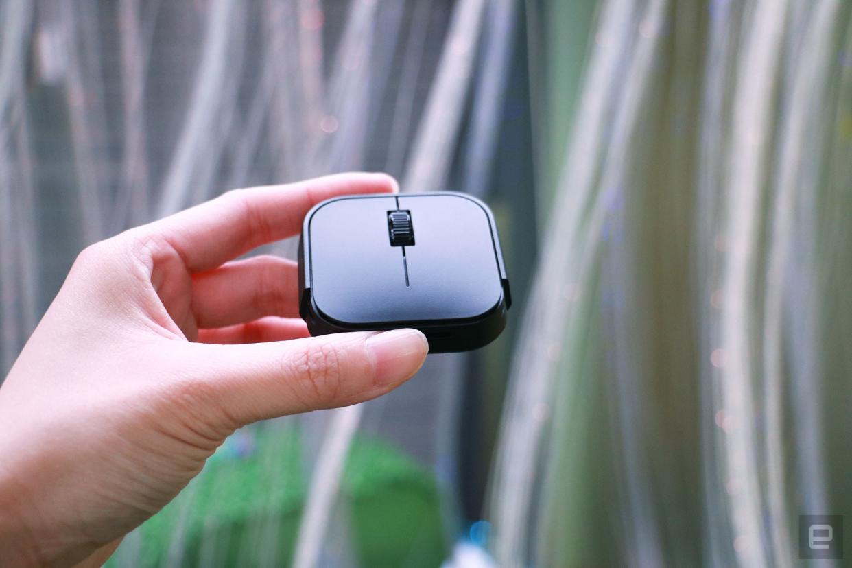 A hand holding the Microsoft Adaptive Mouse in mid-air with its bumper removed.