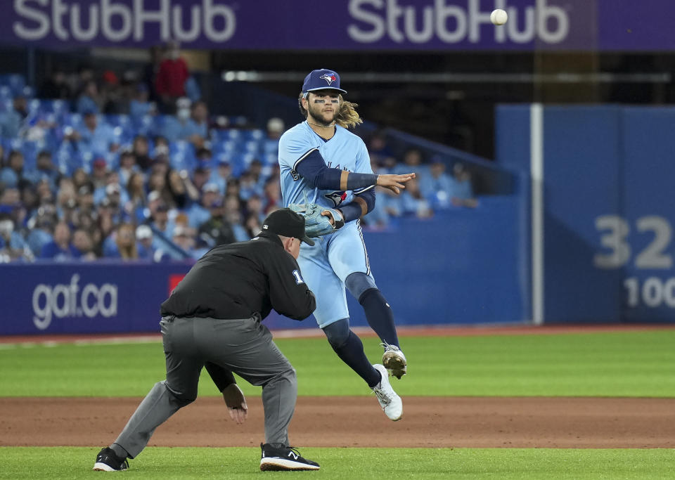 Toronto Blue Jays shortstop Bo Bichette (11) makes a jumping throw to out Seattle Mariners first baseman Ty France (23) at first base during the seventh inning of a baseball game in Toronto, Monday, May 16, 2022. (Nathan Denette/The Canadian Press via AP)