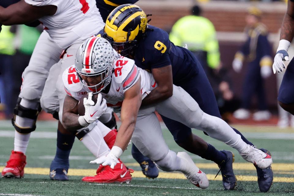 Ohio State Buckeyes running back TreVeyon Henderson is tackled by Michigan Wolverines defensive back Rod Moore in the second half at Michigan Stadium, Nov. 25, 2023.