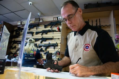 Gun Central general manager Michael McIntyre examines and registers a handgun for sale in El Paso