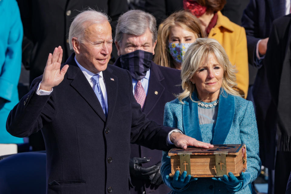 Joe Biden, with his wife, Dr. Jill Biden at his side, holds up his right hand as he is sworn in as U.S. president.  as  looks on.