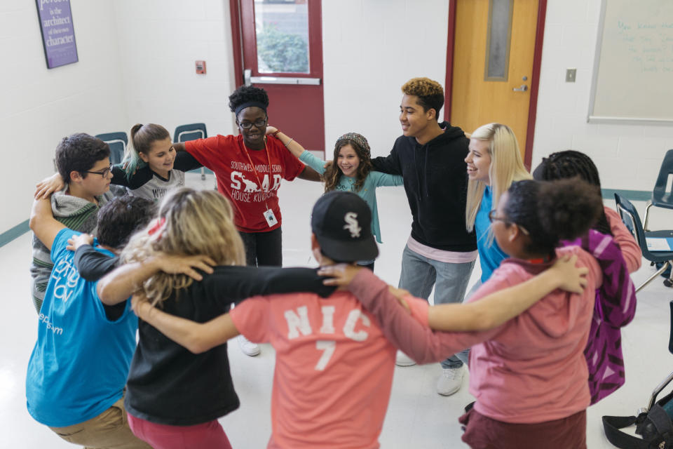 In this Oct. 20, 2017 photo provided by Deep Center, writers and mentors at Southwest Middle School in Savannah, Ga., huddle to launch into the next step of their Deep Center writing workshop. Deep Center works with young writers to share their stories with policy makers, judges, politicians, police officers and the like. (Laura Mulder/Deep Center via AP)