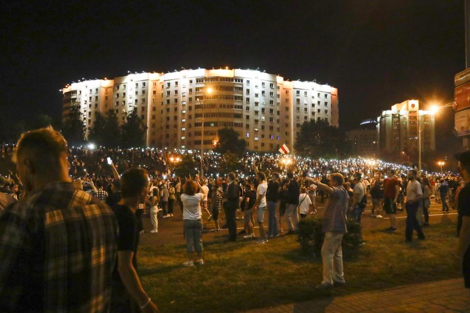 Protesters light their cell phones as they gather to protest against a result of the Belarusian presidential election in Minsk, Belarus, Sunday, Aug. 9, 2020. Police and protesters clashed in Belarus' capital and the major city of Brest on Sunday after the presidential election in which the authoritarian leader who has ruled for a quarter-century sought a sixth term in office. (AP Photo/Sergei Grits)