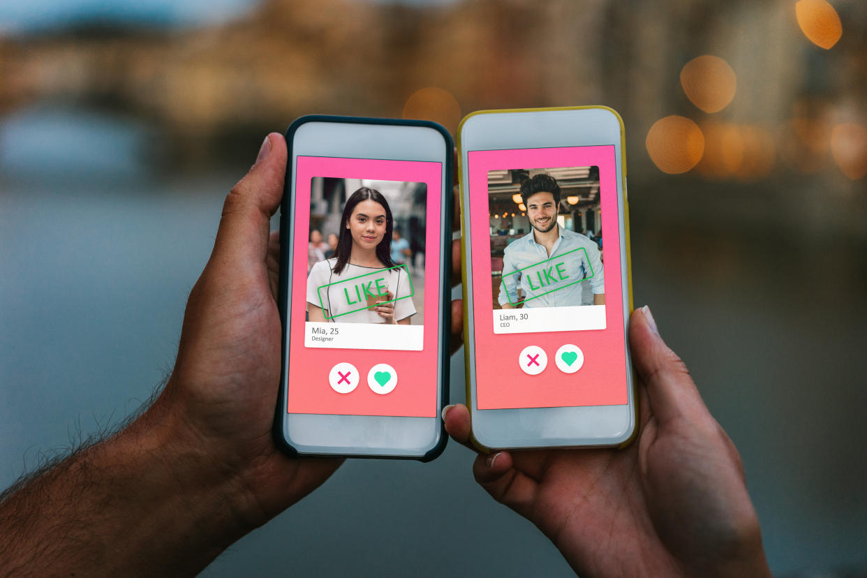 Two hands holding smart phones with an online dating app on the screens.