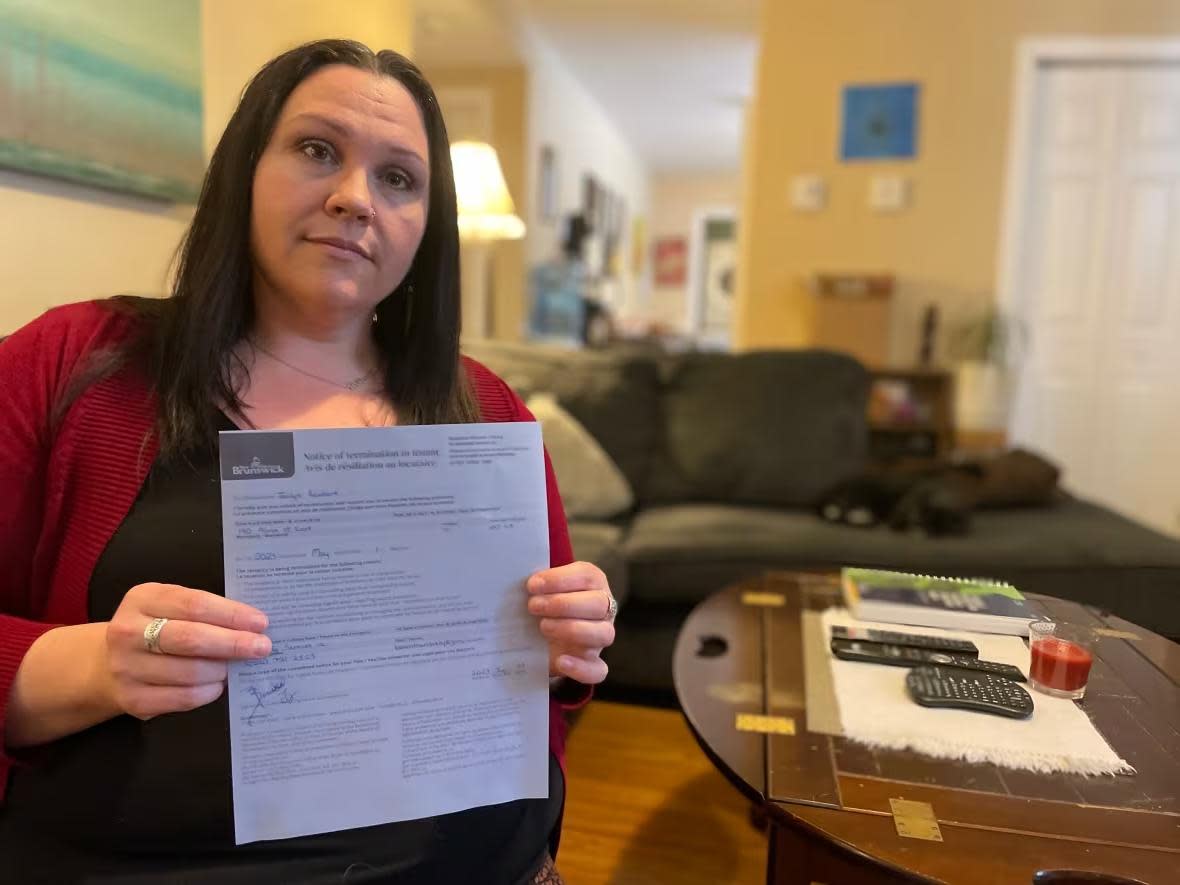 Jaclyn Reinhart, in February, holds up a termination-of-lease notice she received from her Coquitlam, B.C., landlord.   (Robert Jones/CBC - image credit)