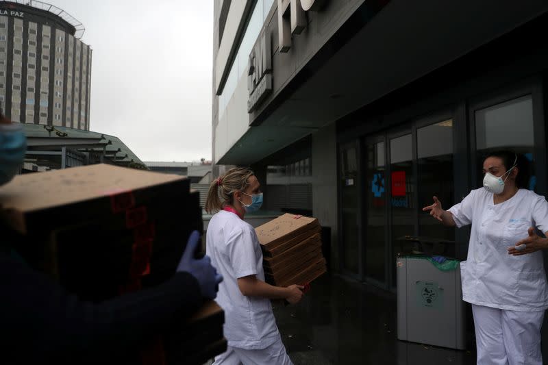Medical staff at La Paz Hospital carry the 20 pizzas being delivered as part of the Food4Heroes initiative during the outbreak of coronavirus disease (COVID-19) in Madrid