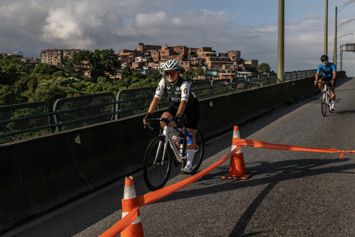 Sara Cardona en la cafetería Safetti mostrando su foto con dos ciclistas profesionales. (Federico Rios/The New York Times)