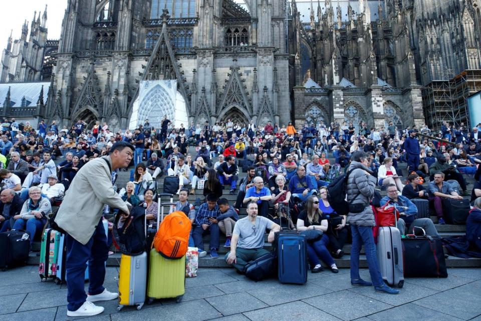 Passengers wait outside the main train station in Cologne (REUTERS)