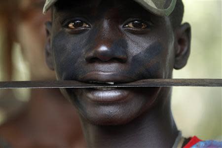 A fighter from the Christian "anti-balaka" militia holds a machete in his mouth at the headquarters in the northern Bangui suburb of Boeing, an area near the Mpoko International Airport of Bangui February 22, 2014. REUTERS/Luc Gnago