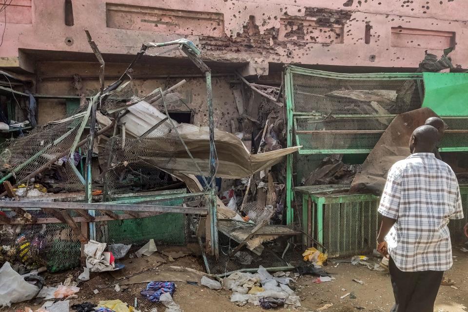 People walk past a medical center building riddled with bullet holes at the Souk Sitta (Market Six) in the south of Khartoum on June 1, 2023. / Credit: AFP via Getty Images