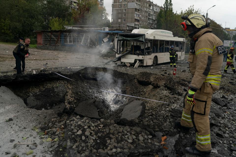 Firefighters and police officers work on a site where an explosion created a crater on the street after a Russian attack in Dnipro, Ukraine, on Oct. 10.