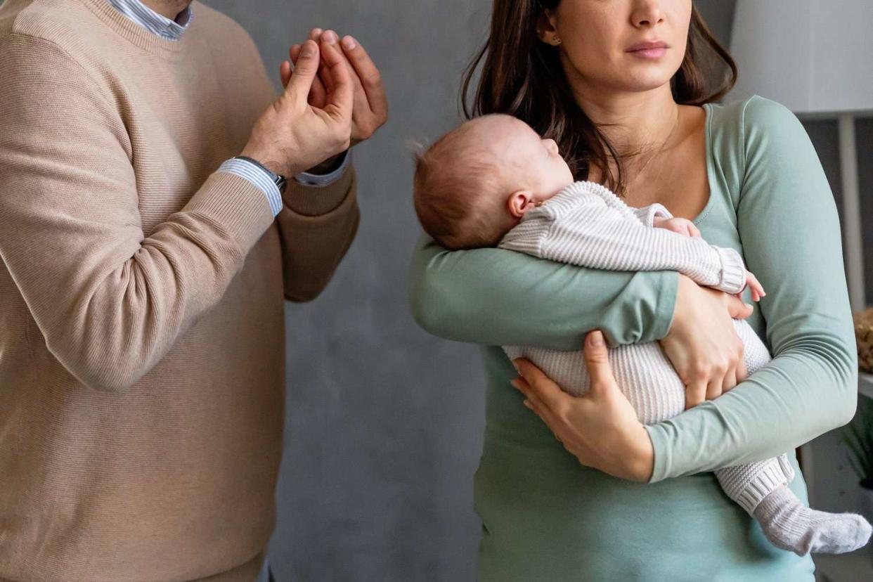 <p>Getty</p> unhappy father with baby and wife