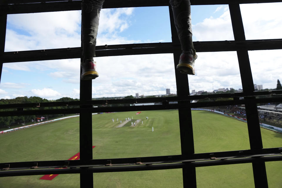 A scorer dangles his feet from the scoreboard on the second day of the Test cricket match between Zimbabwe and West Indies at Queens Sports Club in Bulawayo, Zimbabwe, Sunday,Feb, 5, 2023. (AP Photo/Tsvangirayi Mukwazhi)