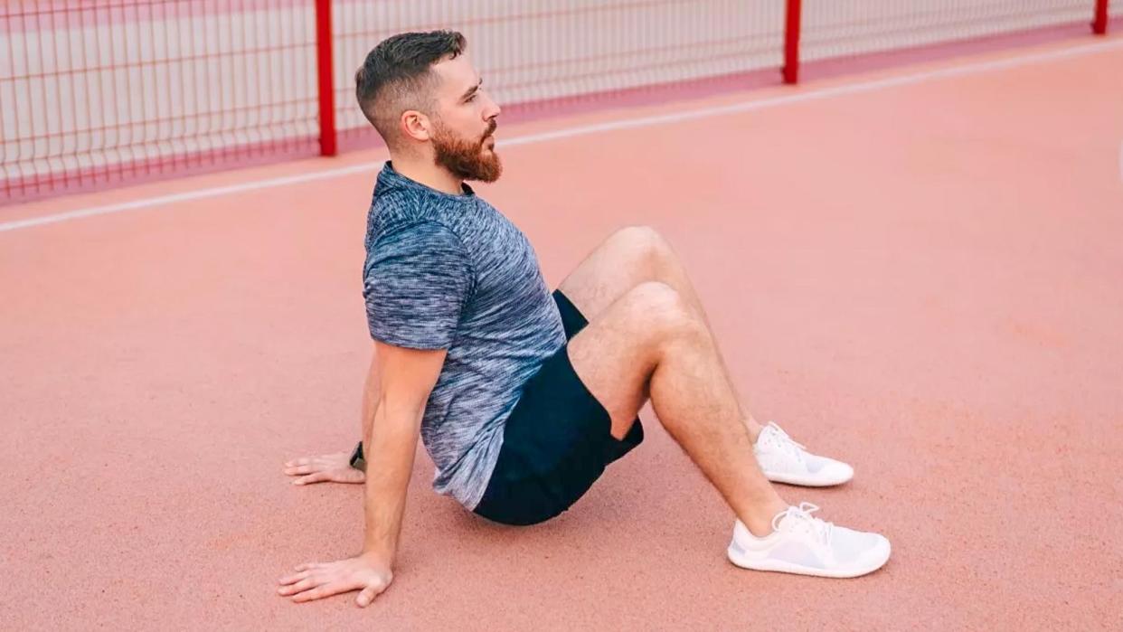  Crab walk: Man in a park sitting down with knees bent and hands placed behind his hips 