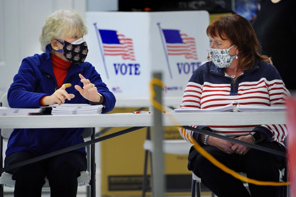 Empleadas electorales Sheila McDonough, izquierda, y Kathleen Reid conversan mientras aguardan la llegada de votantes en South Portland, Maine, martes 2 de noviembre de 2021. (AP Foto/Robert F. Bukaty)