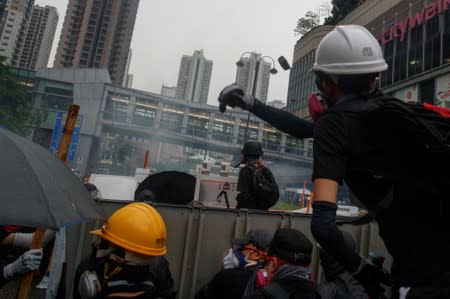 An anti-extradition bill protester throws a stone at police during clashes in Tsuen Wan in Hong Kong