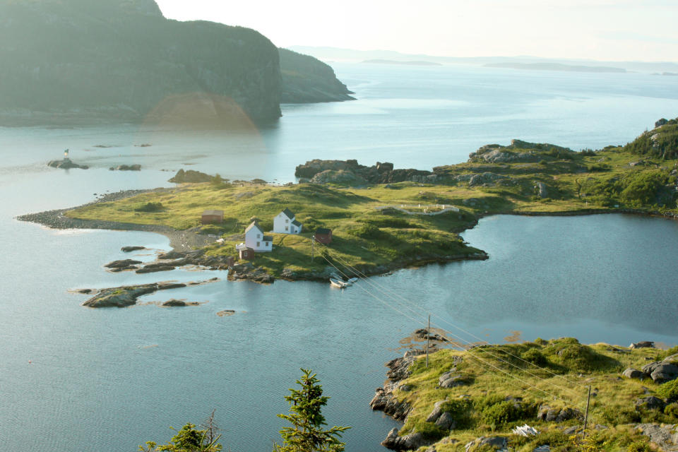 Isolated house on a small island with surrounding water and distant hills