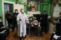 FILE - In this Saturday, May 9, 2020 file photo, the Rev. Fabian Arias performs an in-home service beside the remains of Raul Luis Lopez who died from COVID-19 the previous month, in the Corona neighborhood of the Queens borough of New York. (AP Photo/John Minchillo)