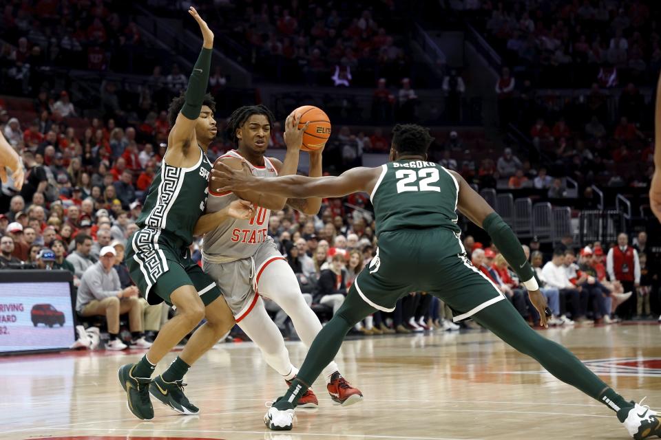 Brice Sensabaugh (10) of the Ohio State Buckeyes attempts to drive the ball past Jaden Akins (3) of the Michigan State Spartans and Mady Sissoko (22) during the first half of the game at the Jerome Schottenstein Center on February 12, 2023 in Columbus, Ohio.