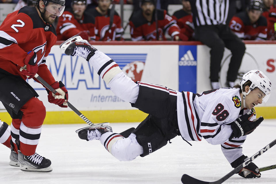 Chicago Blackhawks center Connor Bedard lies on the ice after being checked by New Jersey Devils defenseman Brendan Smith (2) during the first period of an NHL hockey game Friday, Jan. 5, 2024, in Newark, New Jersey (AP Photo/Adam Hunger)