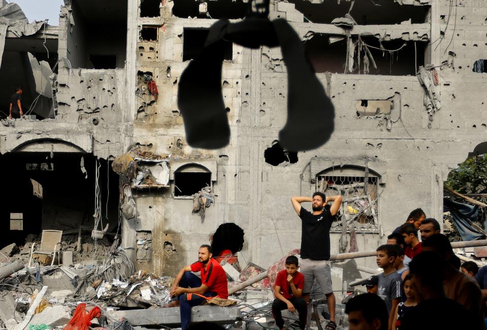 加薩地區遭以色列轟炸，民宅全遭炸毀，民眾看著救難人員搜救。（路透社）