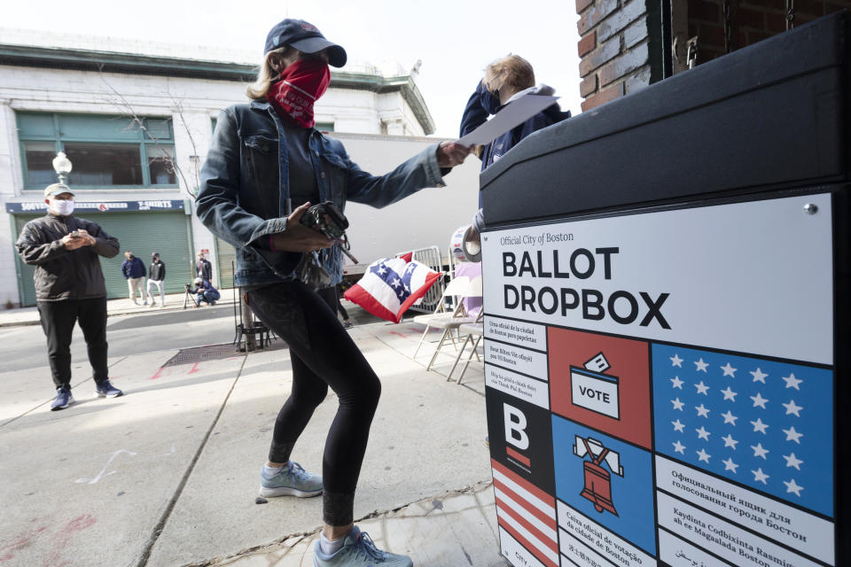 A woman places her ballot in a dropbox after voting at Fenway Park, Saturday, Oct. 17, 2020, in Boston. (AP Photo/Michael Dwyer)