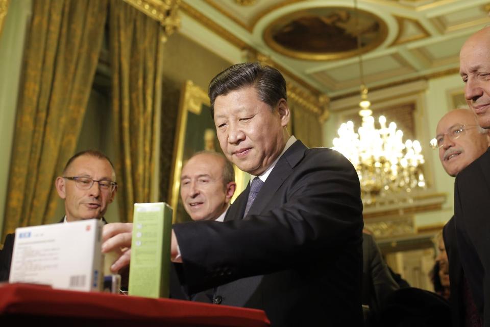 Chinese President Xi Jinping looks at local products during a visit before a dinner at the town hall in Lyon, central France, Tuesday, March 25, 2014. Xi Jinping arrived in France for a three-day state visit. (AP Photo/Laurent Cipriani, Pool)