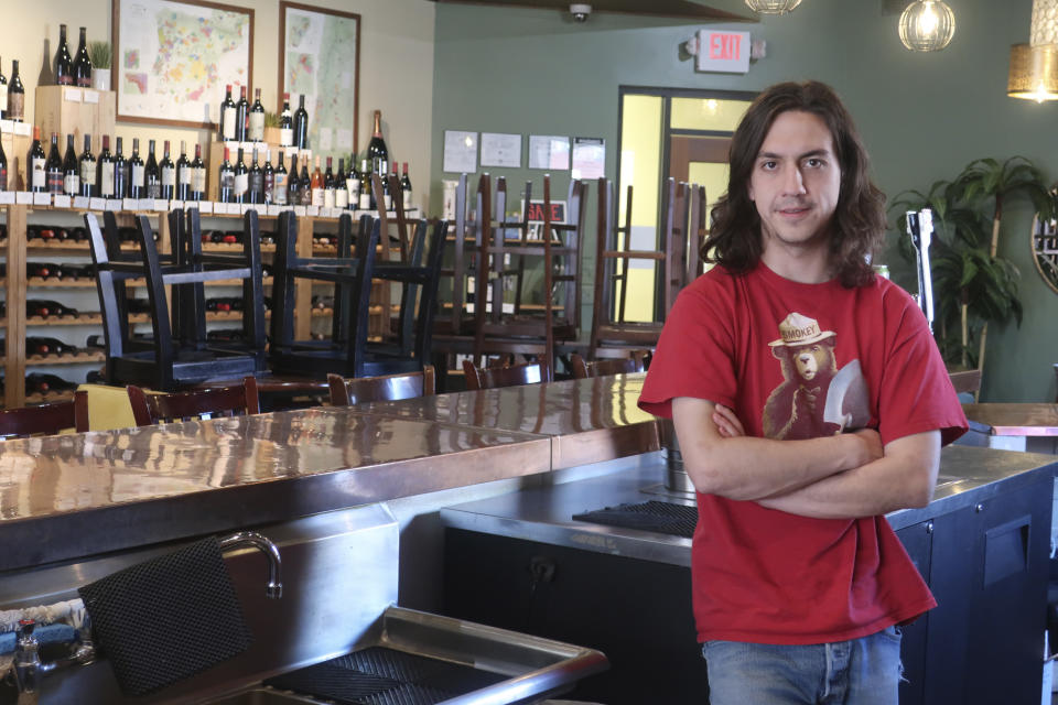 Guillermo Camacho speaks about the closure of a wine shop where he works in Flagstaff, Ariz., Tuesday, March 17, 2020. The mayor of Flagstaff ordered restrictions on restaurants and the closure of other businesses in a bid to stop the spread of the new coronavirus. (AP Photo/Felicia Fonseca)