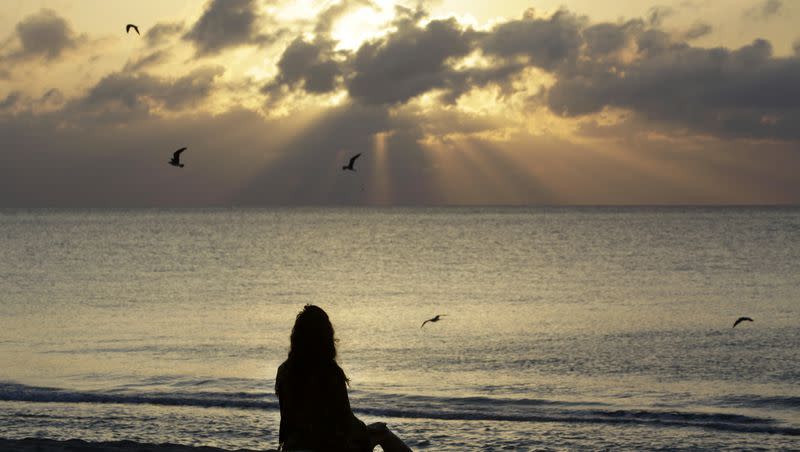 A woman meditates on the beach in Miami Beach, Fla., on Wednesday, April 28, 2010.