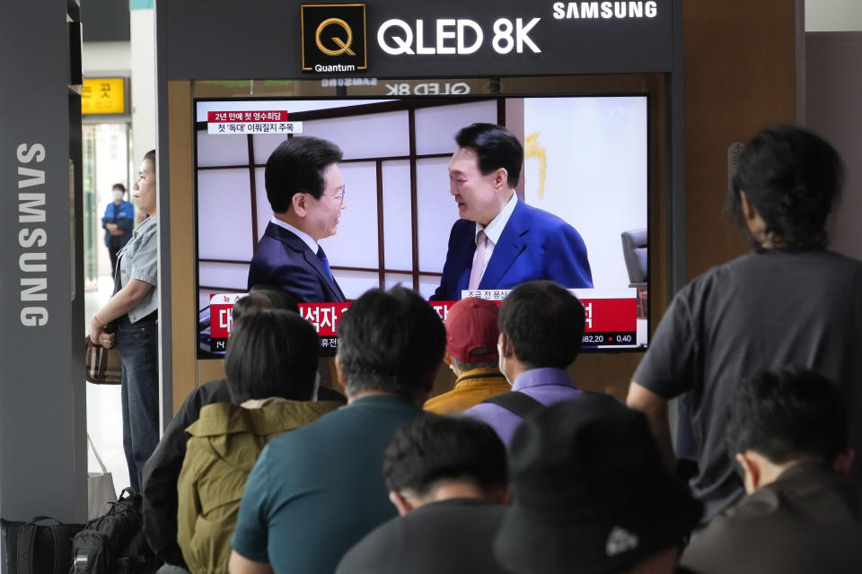 People watch a TV screen showing South Korean President Yoon Suk Yeol, right, meeting with main opposition Democratic Party leader Lee Jae-myung, during a news program at the Seoul Railway Station in Seoul, South Korea, Monday, April 29, 2024. (AP Photo/Ahn Young-joon)