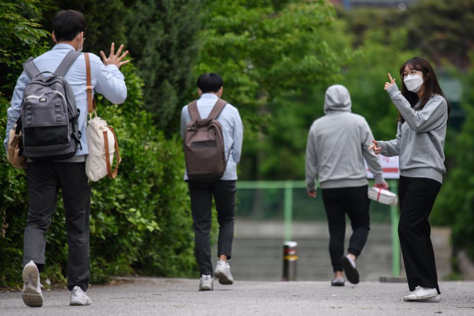 A staff member (R) greets students as they arrive at Kyungbock High School in Seoul on May 20, 2020. - Hundreds of thousands of South Korean students returned to classes as schools started reopening after more than a two-month delay over the coronavirus outbreak. (Photo by Ed JONES / AFP) (Photo by ED JONES/AFP via Getty Images)
