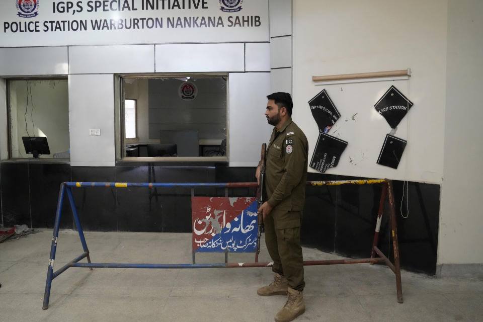 A police officer examines the damaged area of police station in Warburton, an area of district Nankana, Pakistan, Sunday, Feb. 12, 2023. Hundreds of Muslims descended on a police station in Pakistan's eastern Punjab province on Saturday, snatched Waris, a blasphemy suspect from his cell and took him outside and lynched him, police said. (AP Photo/K.M. Chaudary)