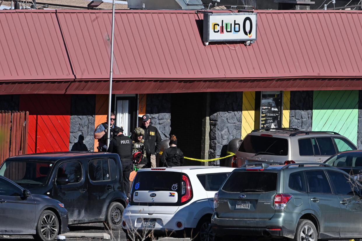 Several police officers and FBI agents investigate the scene in front of Club Q.