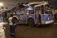 A policeman watches as a bus, destroyed in an earlier explosion, is towed away in Volgograd December 30, 2013. A bomb ripped apart a bus in Volgograd on Monday, killing 14 people in the second deadly attack blamed on suicide bombers in the southern Russian city in 24 hours and raising fears of Islamist attacks on the Winter Olympics. REUTERS/Sergei Karpov (RUSSIA - Tags: CIVIL UNREST CRIME LAW DISASTER TRANSPORT)