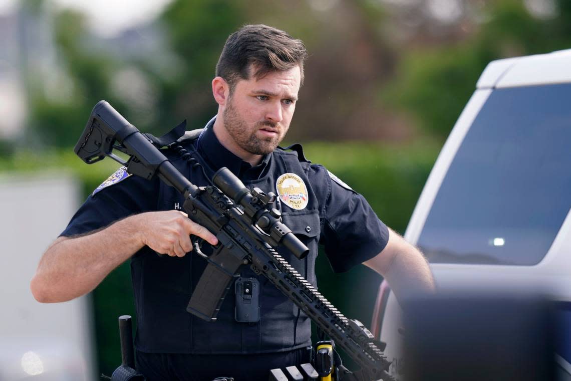 A law enforcement officer carries a rifle as people are evacuated from the Allen Premium Outlets following a shooting on Saturday.