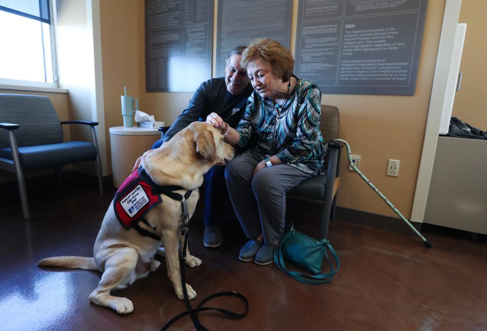 Bobbie West, right, and her husband Ralph West petted facility dog "Zeus" at the Norton Cancer Institute in Louisville, Ky. on Feb. 20, 2024. They were waiting for Bobbie to receive her 12th infusion treatment for Alzheimer's at the facility.