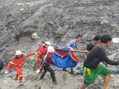 In this photo released from Myanmar Fire Service Department, rescuers carry a recovered body of a victim in a landslide from a jade mining area in Hpakant, Kachin state, northern Myanmar Thursday, July 2, 2020. Myanmar government says a landslide at a jade mine has killed dozens of people. (Myanmar Fire Service Department via AP)