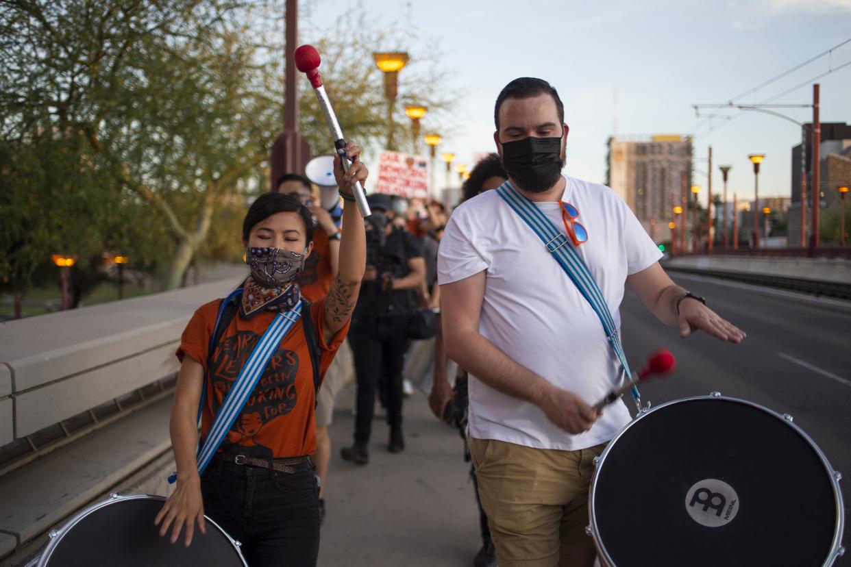 Shela Yu (left) and Jake White (right), members of the group Samba De Cavalo, march down Central Avenue near Margaret T. Hance Park in Phoenix as part of the Strength in Unity rally in support of the Valley's Asian American and Pacific Islander communities on April 24, 2021.