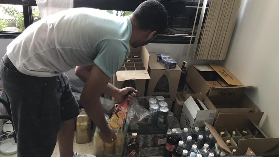 Cristian Roa recogiendo una botella de unas cajas.