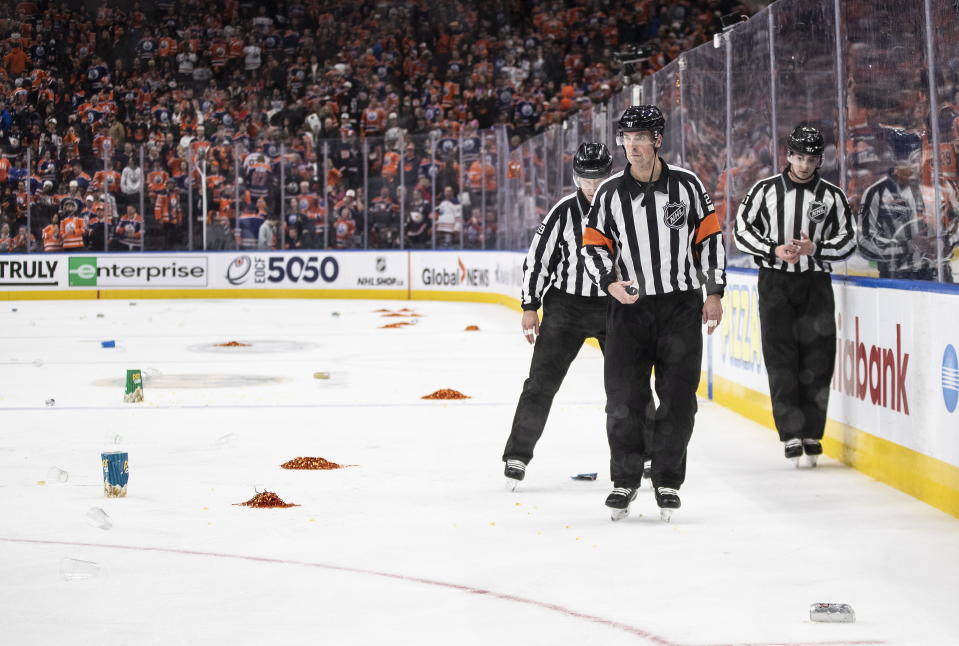Referees skate past garbage thrown on the ice after the Los Angeles Kings win over the Edmonton Oilers during overtime of Game 1 of an NHL Stanley Cup first-round hockey playoff series in Edmonton, Alberta, Monday, April 17, 2023. (Jason Franson/The Canadian Press via AP)