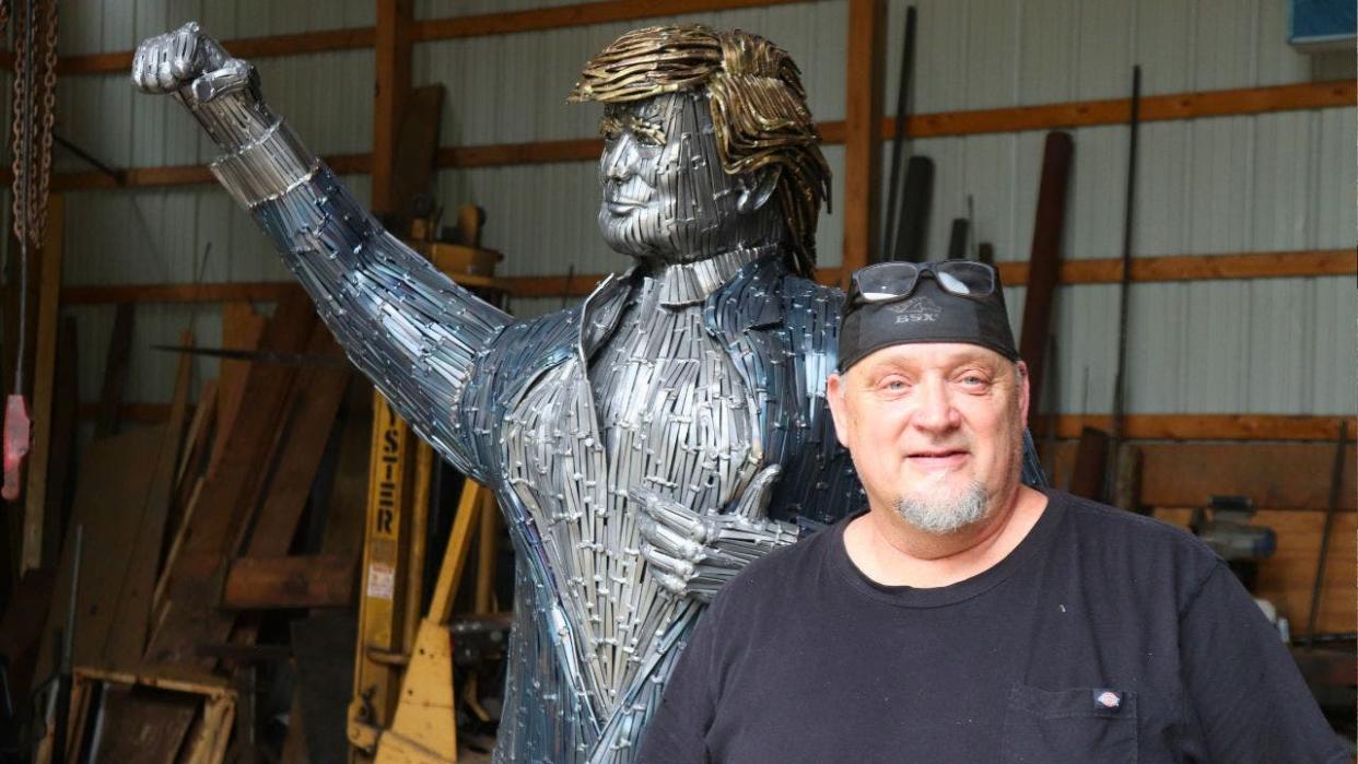 Butler artist bill Secunda standing in front of nail based structure of former President Trump.