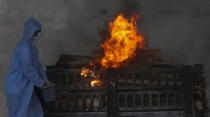 A municipal worker in personal protective suit performs last rites during the cremation of a COVID-19 victim in Vasai, on the outskirts of Mumbai, India, Thursday, April 15, 2021. India has been overwhelmed by hundreds of thousands of new coronavirus cases daily, bringing pain, fear and agony to many lives as lockdowns have been placed in Delhi and other cities around the country. (AP Photo/Rafiq Maqbool)