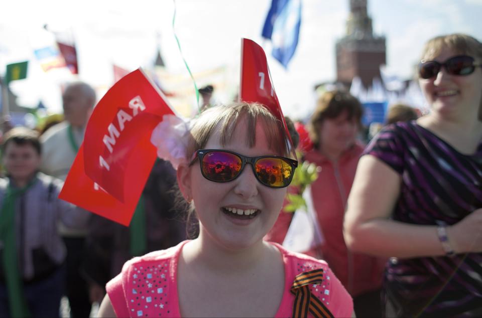 A girl and her mother smile as they march with members of Russian Trade Unions during the May Day celebration in Red Square, Moscow, Russia, on Thursday, May 1, 2014. About 100,000 people have marched through Red Square to celebrate May Day, the first time the annual parade has been held on the vast cobblestoned square outside the Kremlin since the fall of the Soviet Union in 1991. (AP Photo/Ivan Sekretarev)