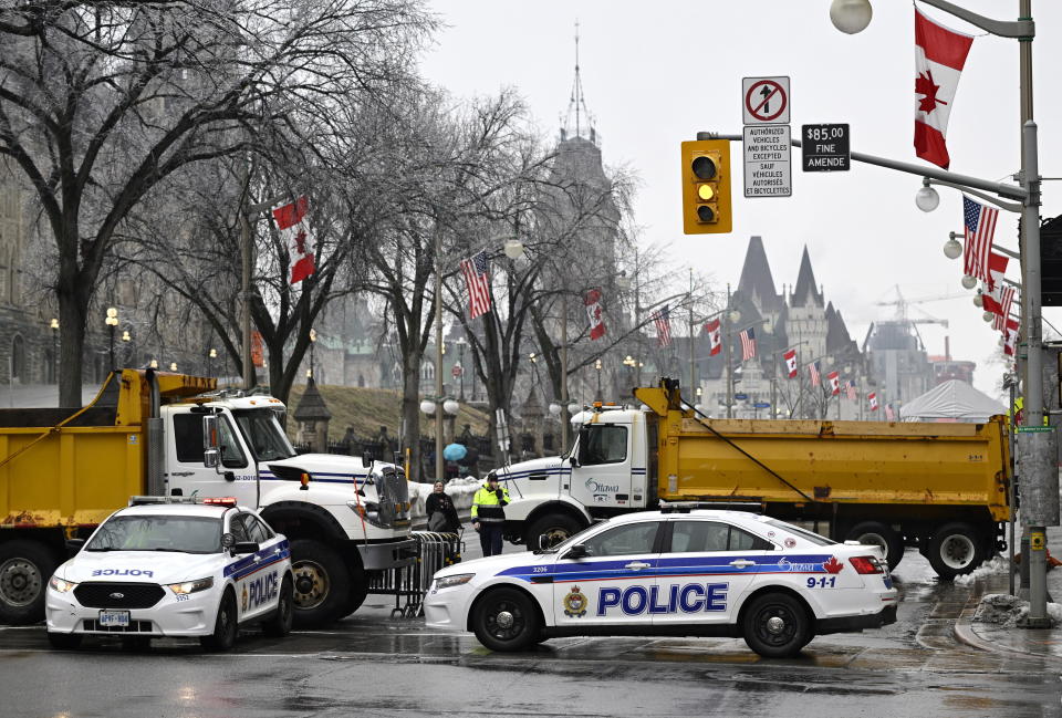 Police vehicles and dump trucks control access to Wellington Street in front of Parliament Hill in Ottawa, before the visit of U.S. President Joe Biden to Canada, on Thursday, March 23, 2023. (Justin Tang /The Canadian Press via AP)