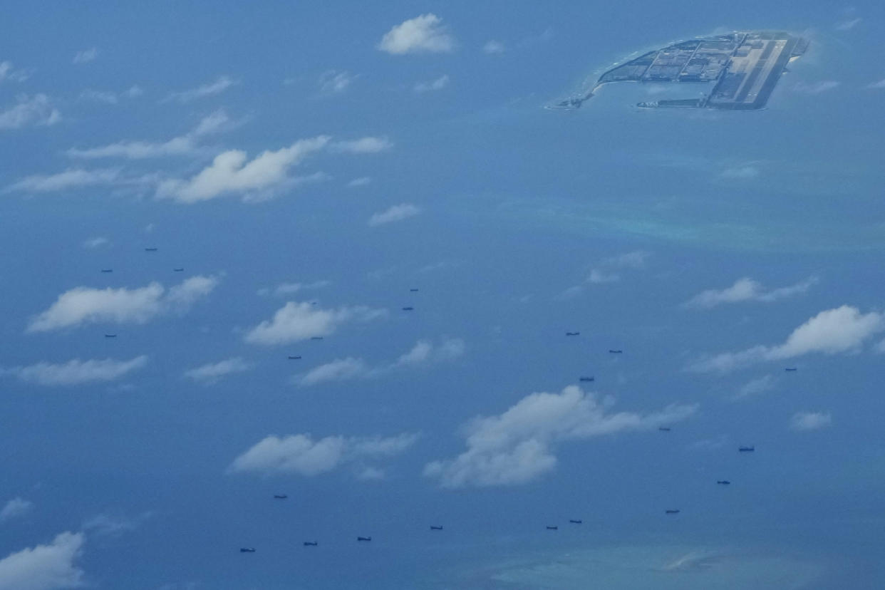 Boats are seen beside Chinese structures and buildings on the man-made Fiery Cross Reef at the Spratlys group of islands in the South China Sea on Sunday March 20, 2022. China has fully militarized at least three of several islands it built in the disputed South China Sea, arming them with anti-ship and anti-aircraft missile systems, laser and jamming equipment and fighter jets in an increasingly aggressive move that threatens all nations operating nearby, a top U.S. military commander said Sunday. (AP Photo/Aaron Favila)