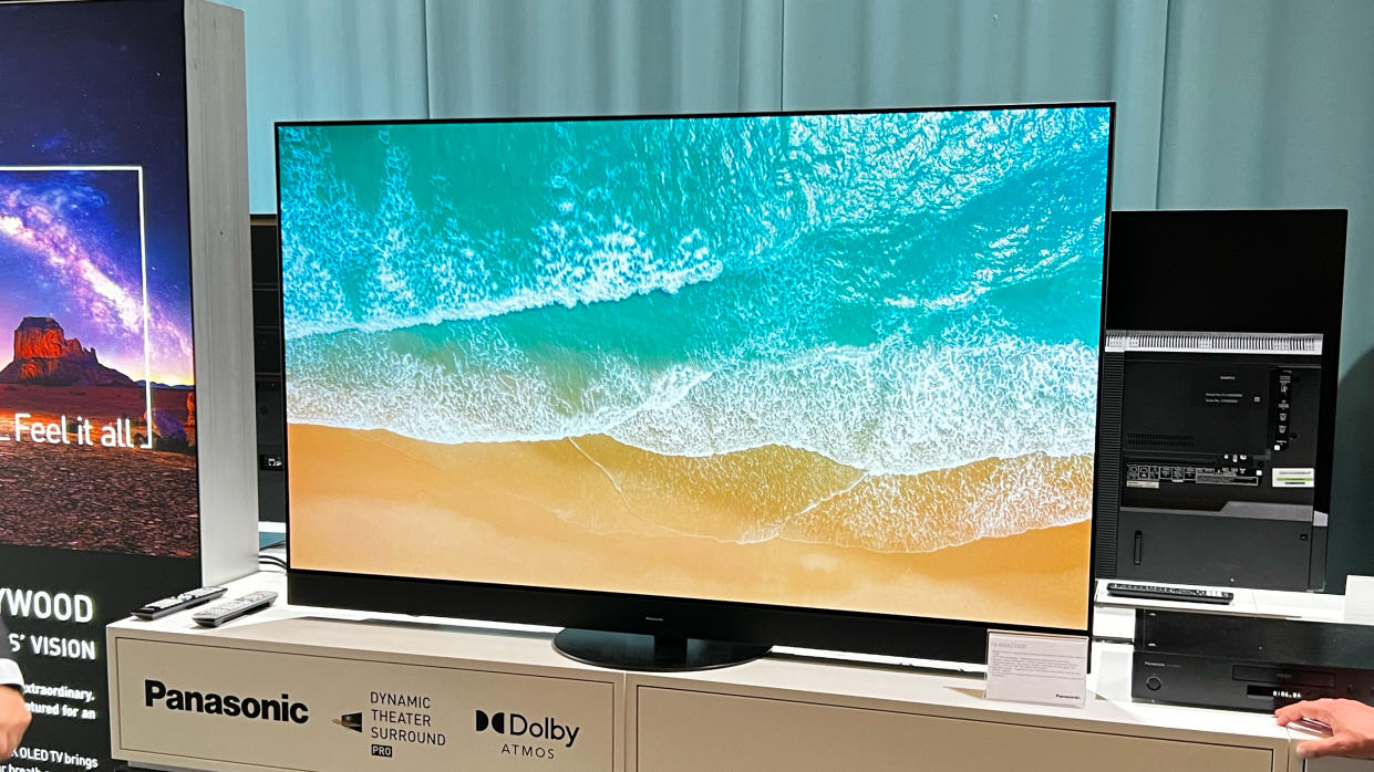  Panasonic LZ1500 TV shows an image of waves rolling over sand. The TV is standing on a shelf at a trade show 