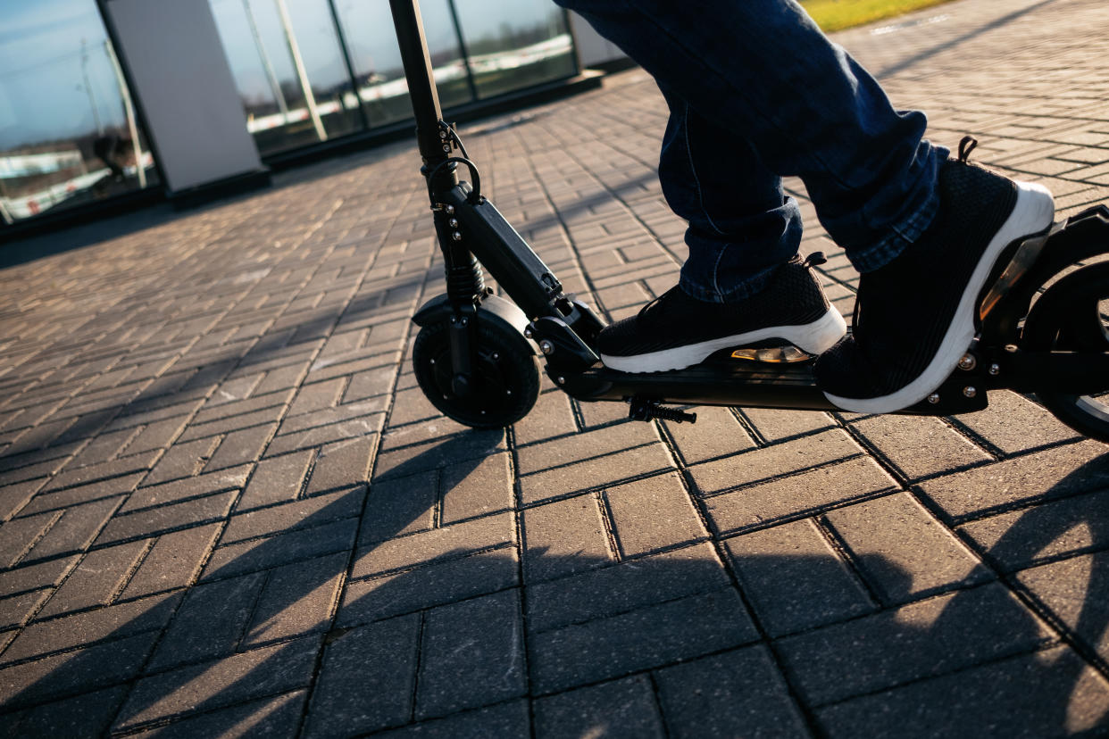Close up view of legs of man on electric scooter outdoor.