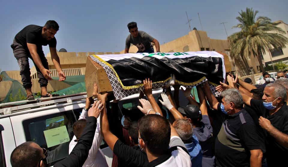 Mourners load the flag-draped coffin of Hisham al-Hashimi during his funeral, in the Zeyouneh area of Baghdad, Iraq, Tuesday, July, 7, 2020. Al-Hashimi, an Iraqi analyst who was a leading expert on the Islamic State and other armed groups was shot dead in Baghdad on Monday. (AP Photo/Khalid Mohammed)