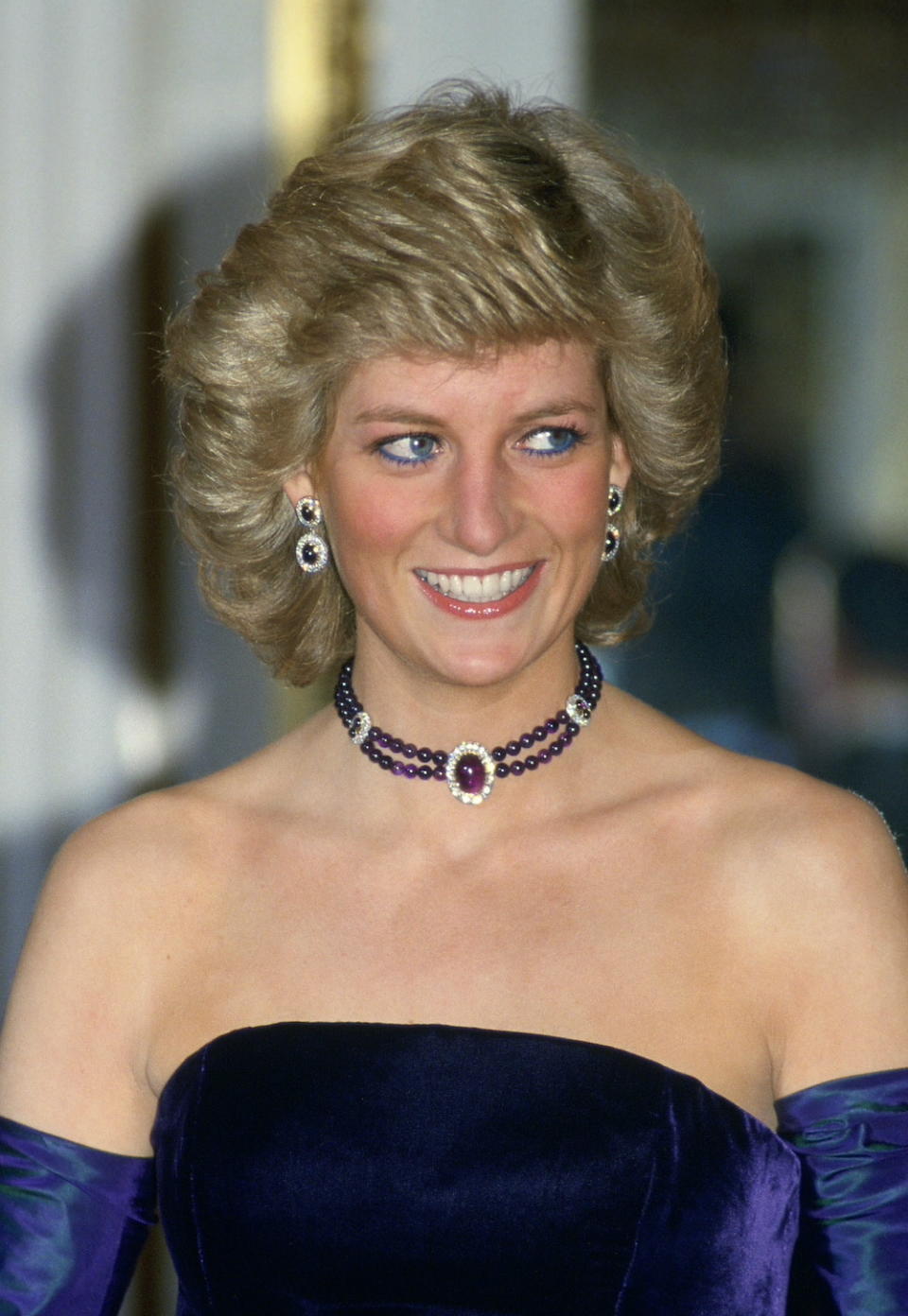 Diana, Princess Of Wales, Wearing A Purple Velvet Sleeveless Evening Dress Designed By Catherine Walker With Matching Choker And Earrings For A Performance Of Mozart's Opera 